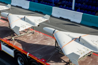 Two white military drones attached to the back of a truck.